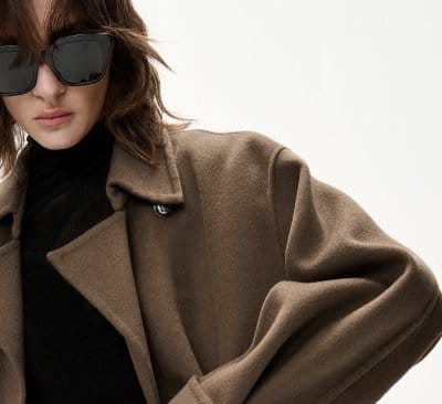 a woman wearing a brown coat and sunglasses