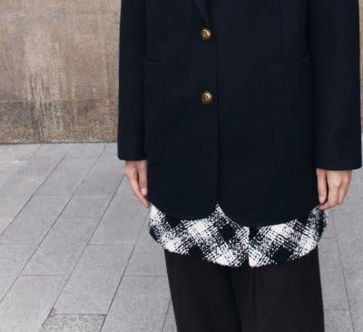 a woman wearing a black and white skirt and a black jacket