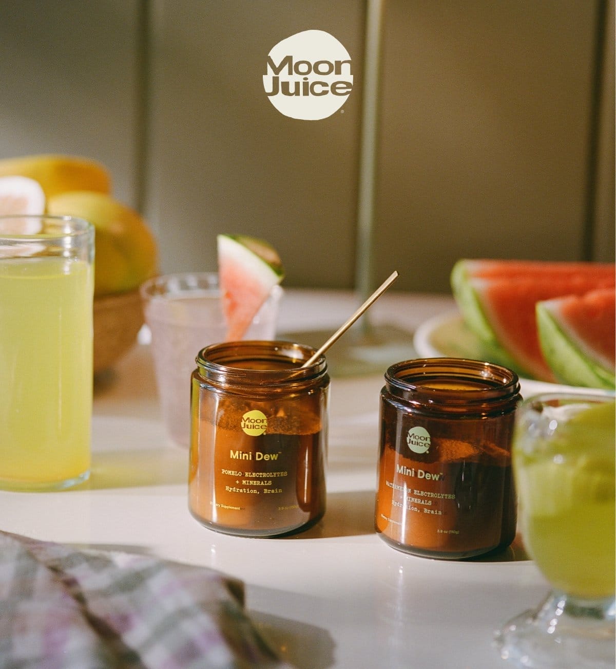 Mini Dew Pomelo and Mini Dew Watermelon jars on countertop with fresh fruit