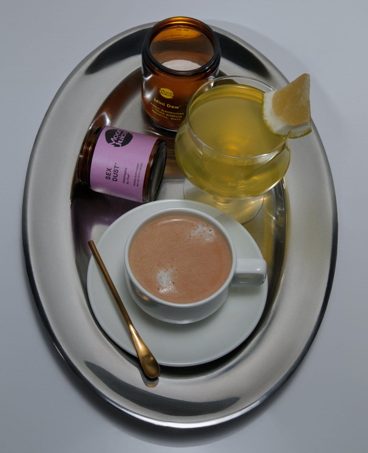 Silver tray with a latte, Mini Dew drink, jar of Sex Dust, and jar of Pomello Mini Dew on it