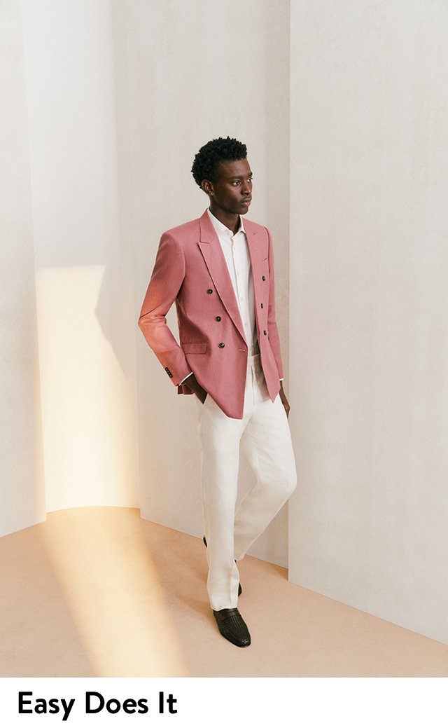 A model wearing a pink double-breasted jacket with a white shirt and white pants.