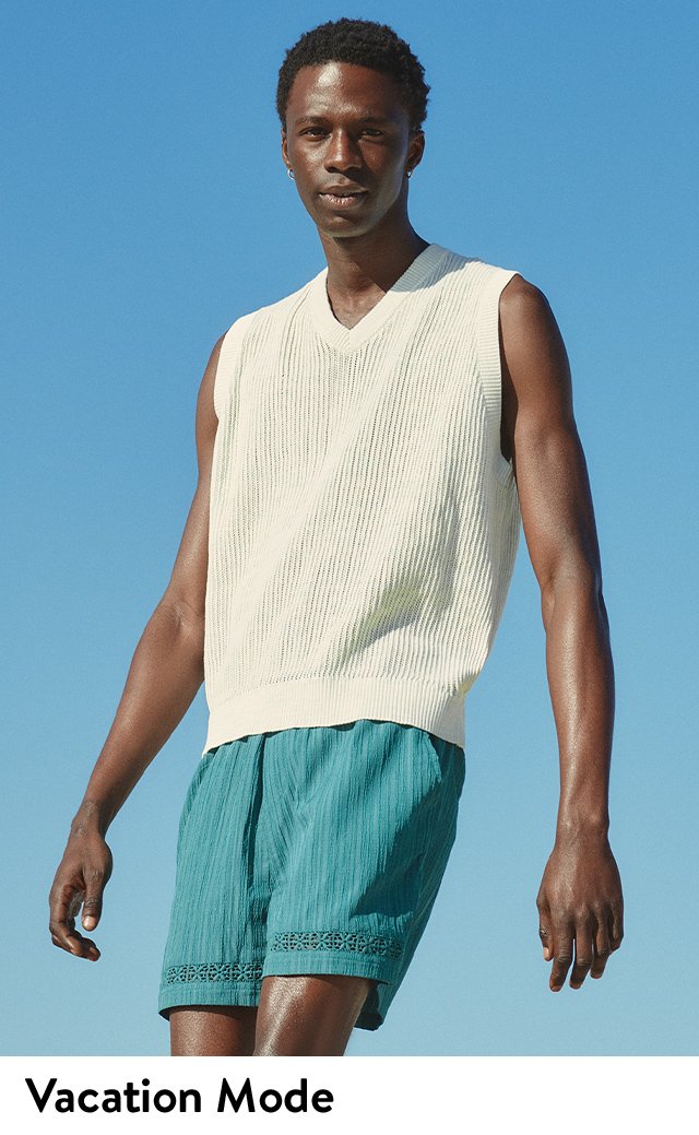 A model wearing a white vest and blue shorts.