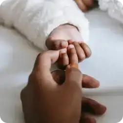 Adult hand holding infant hand