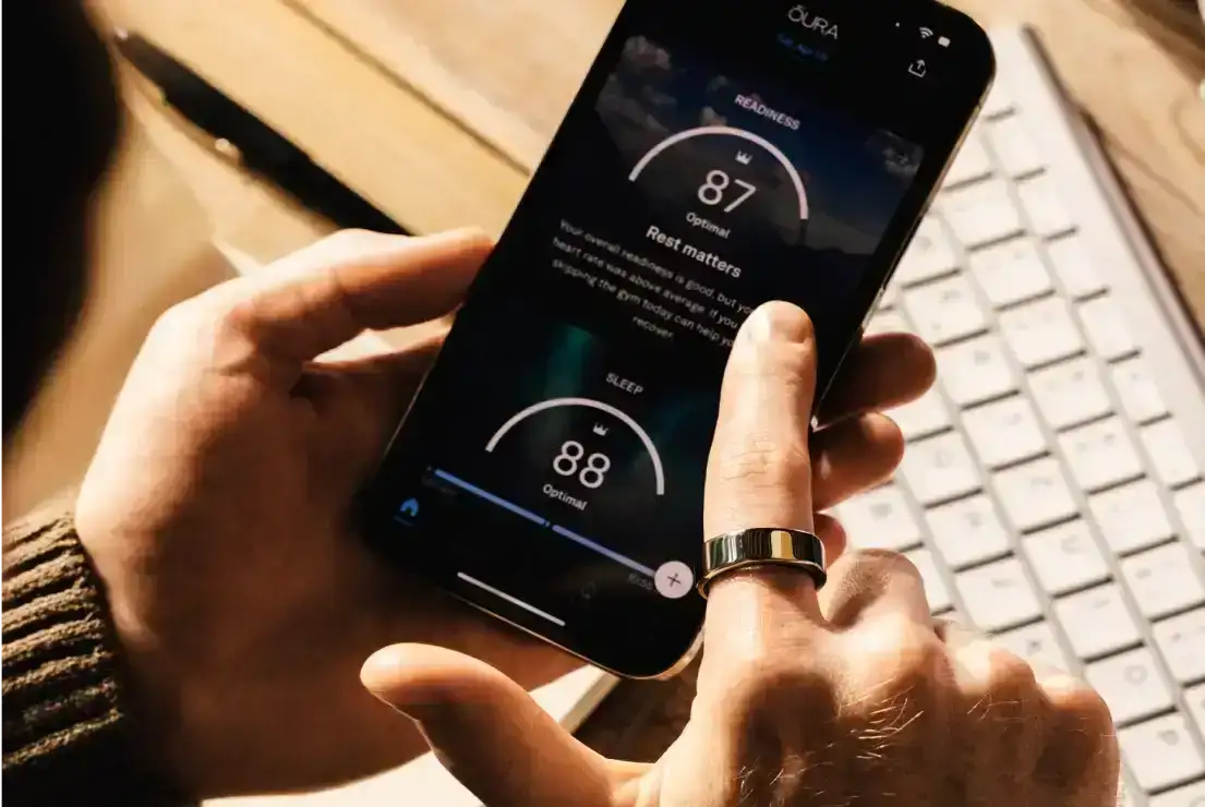 Person wearing Oura Ring holding phone with Oura app open