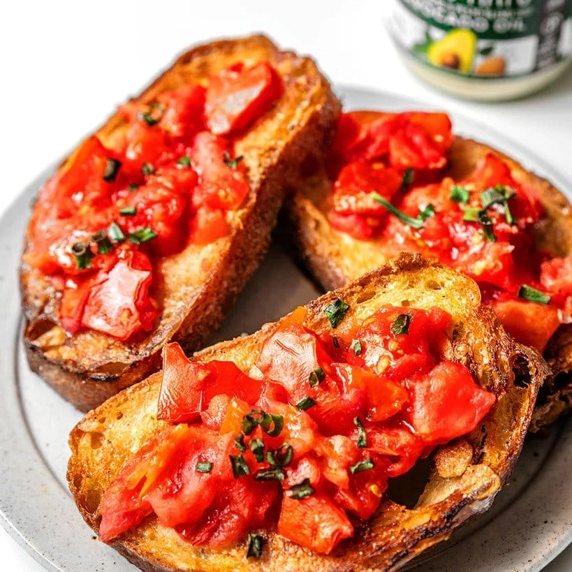 Three slices of toast topped with pesto tomatoes