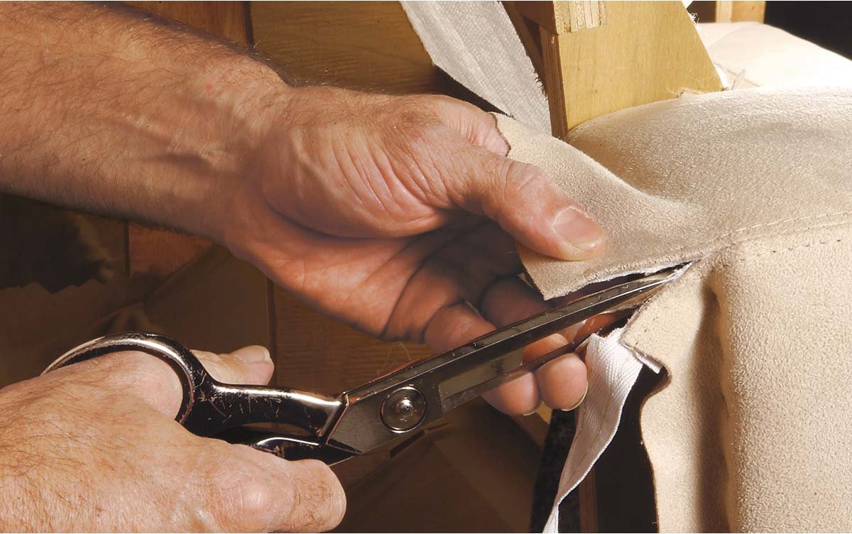 Close-up of a craftperson's hands cutting fabric with scissors