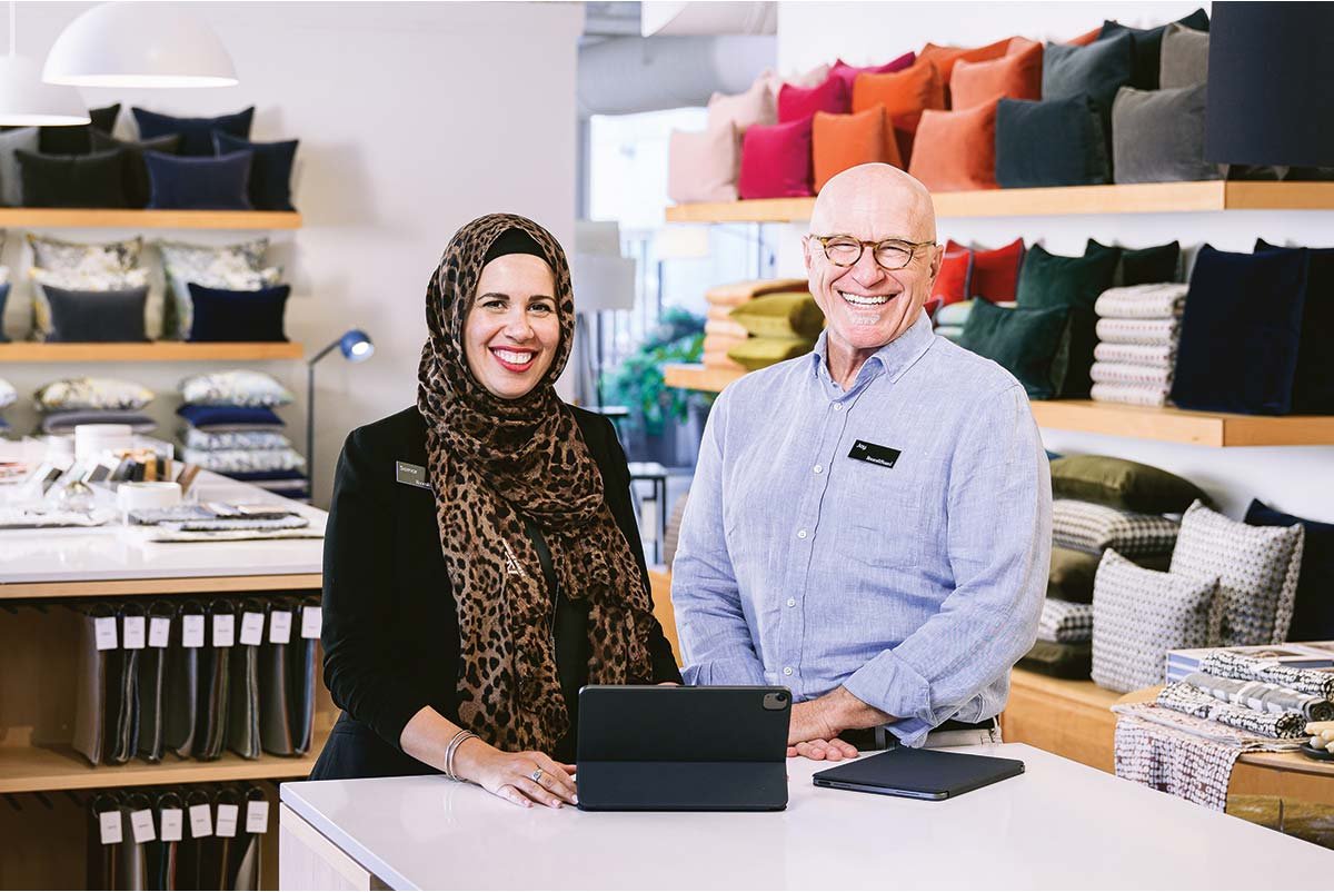 Two smiling design associates standing at a counter with ipads