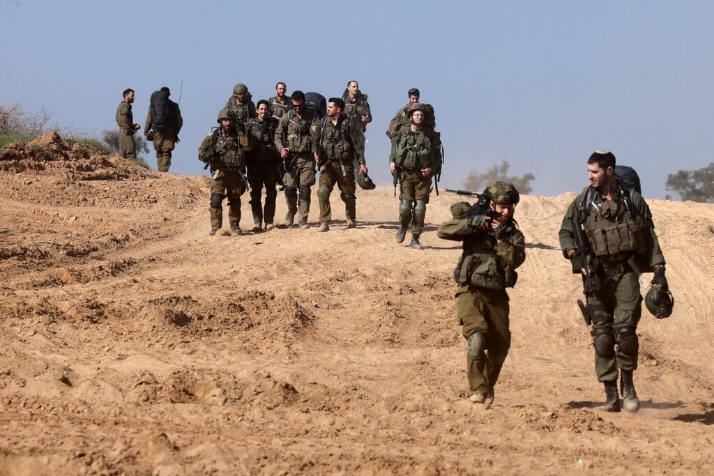 Soldiers walking on dry-looking earth.