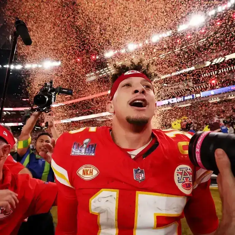 Patrick Mahomes exults against a backdrop of confetti in a stadium.