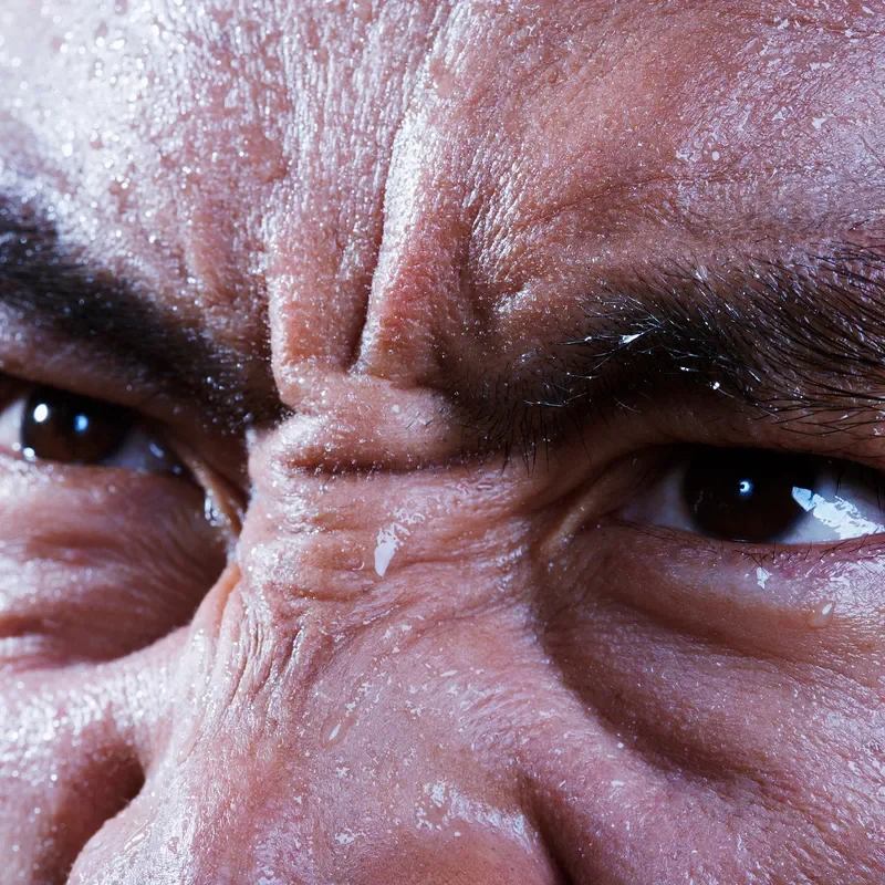 A close up image of a man sweating. 