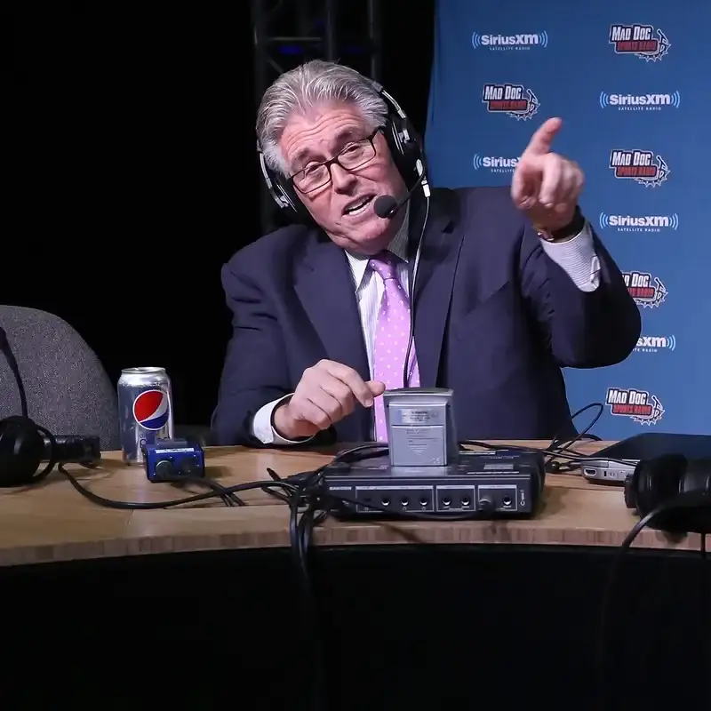 Mike Francesa speaking in a radio recording studio and pointing a finger in the air. 