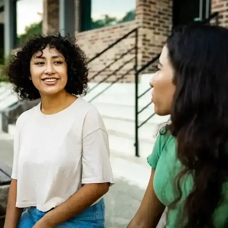 Two people having a conversation on a bench.