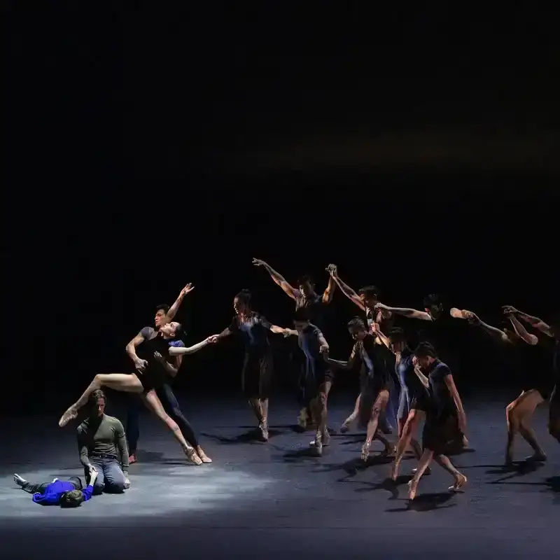 A group of dancers move across a dark stage, photographed by Natalie Keyssar for The New Yorker. 