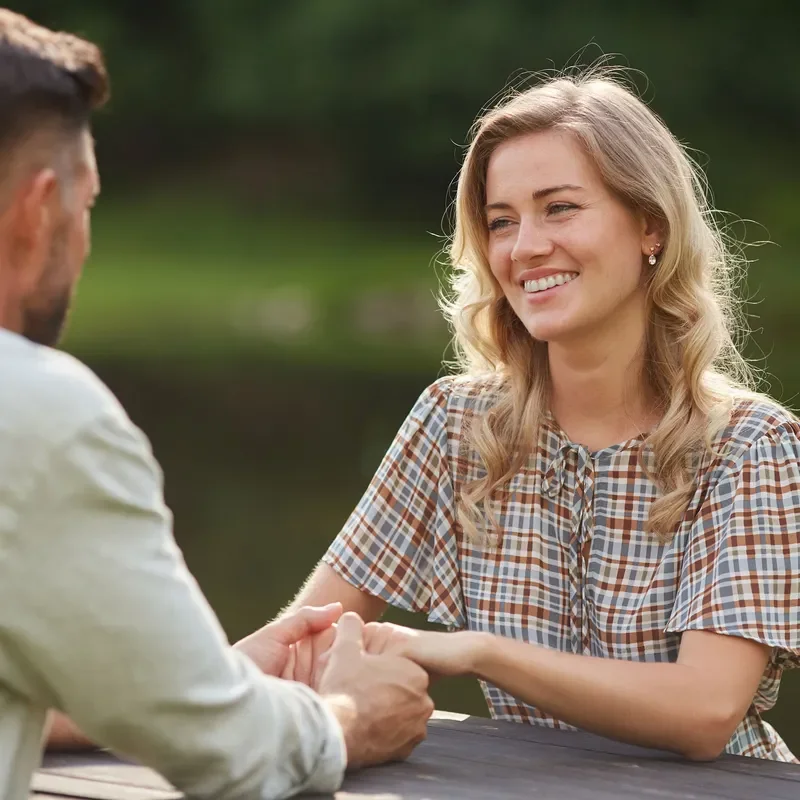 A woman and man holding hands and sitting across a table from each other