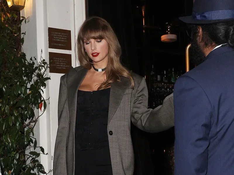 Image may contain: Taylor Swift, Clothing, Coat, Blazer, Jacket, Accessories, Jewelry, Necklace, Adult, Person, and Hat