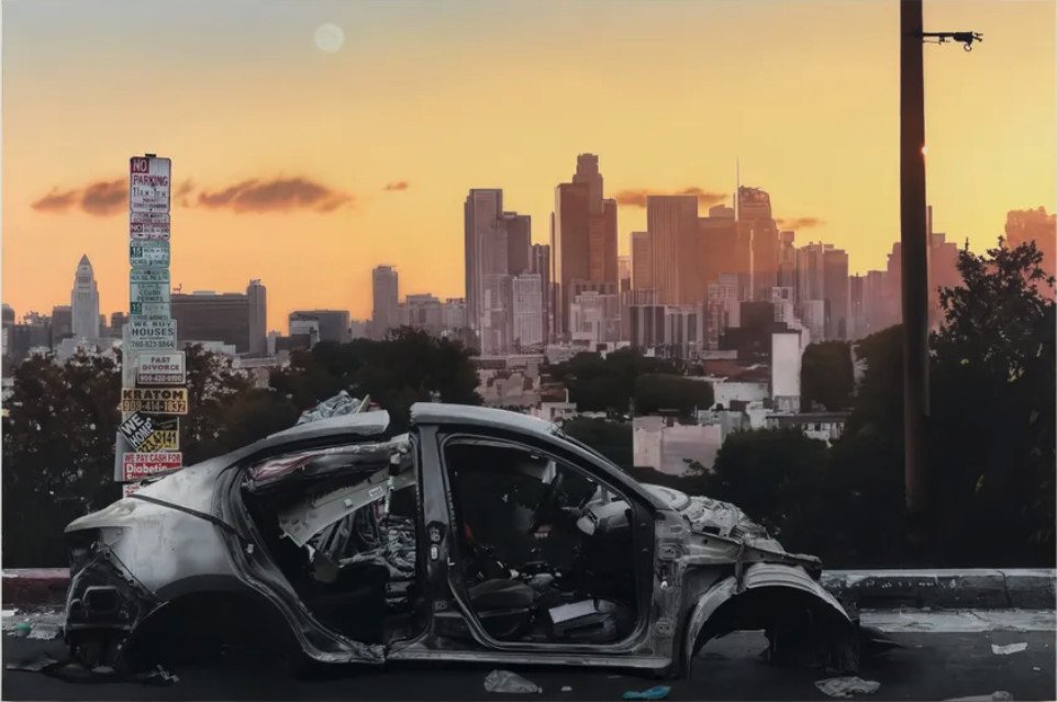 burnt out car against LA skyline backdrop